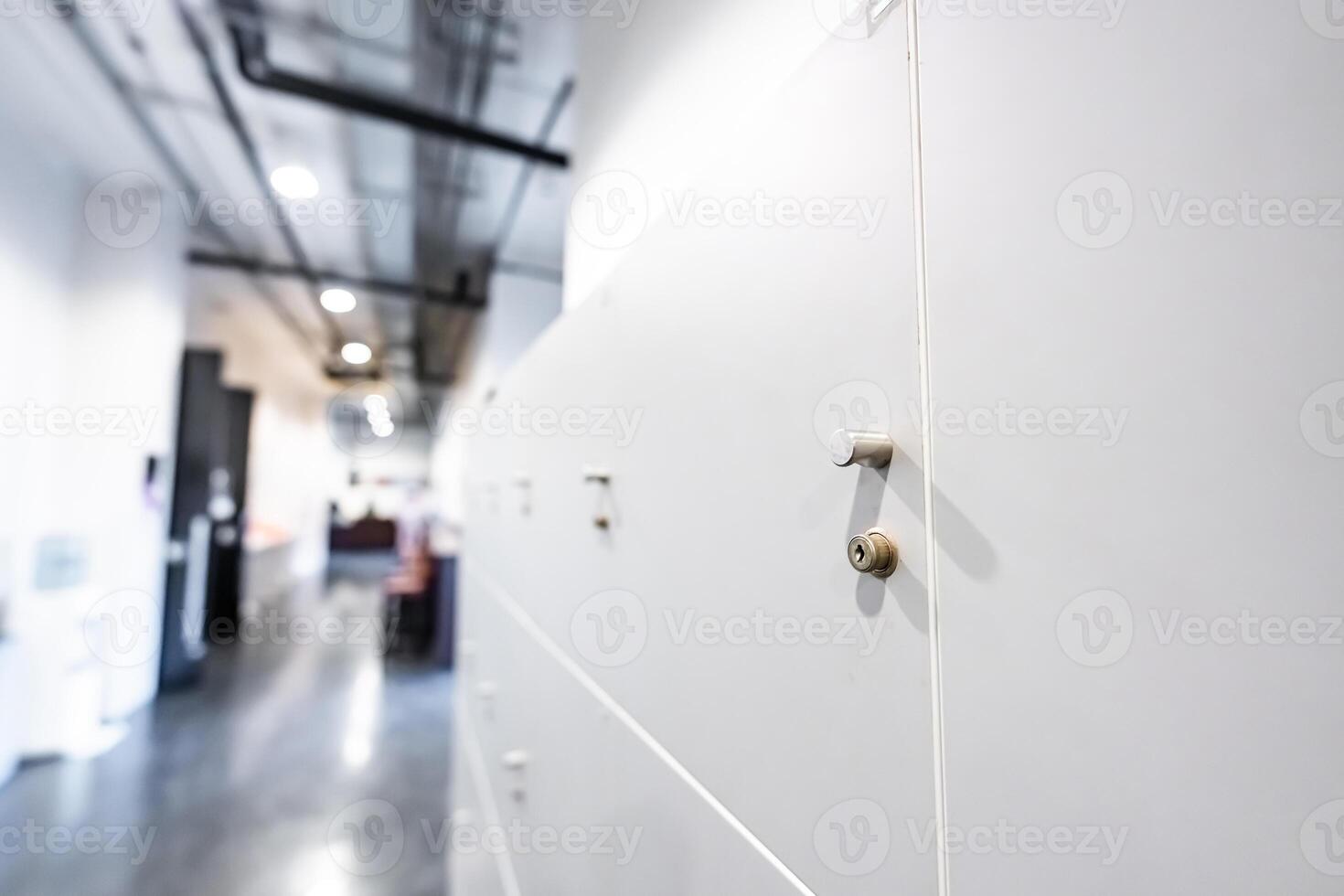 Large gray locker with each locker closed located beside corridors inside building are dimly lit. photo