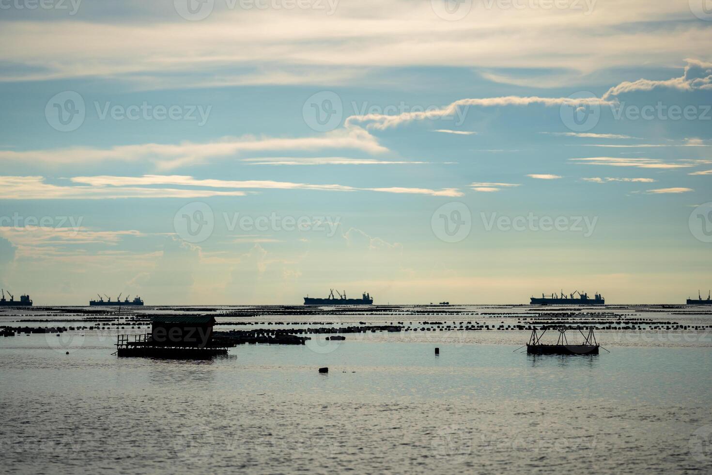 Local fishing boat and container ship are floating on the sea in clear sky day, Sriracha, Chonburi province. photo