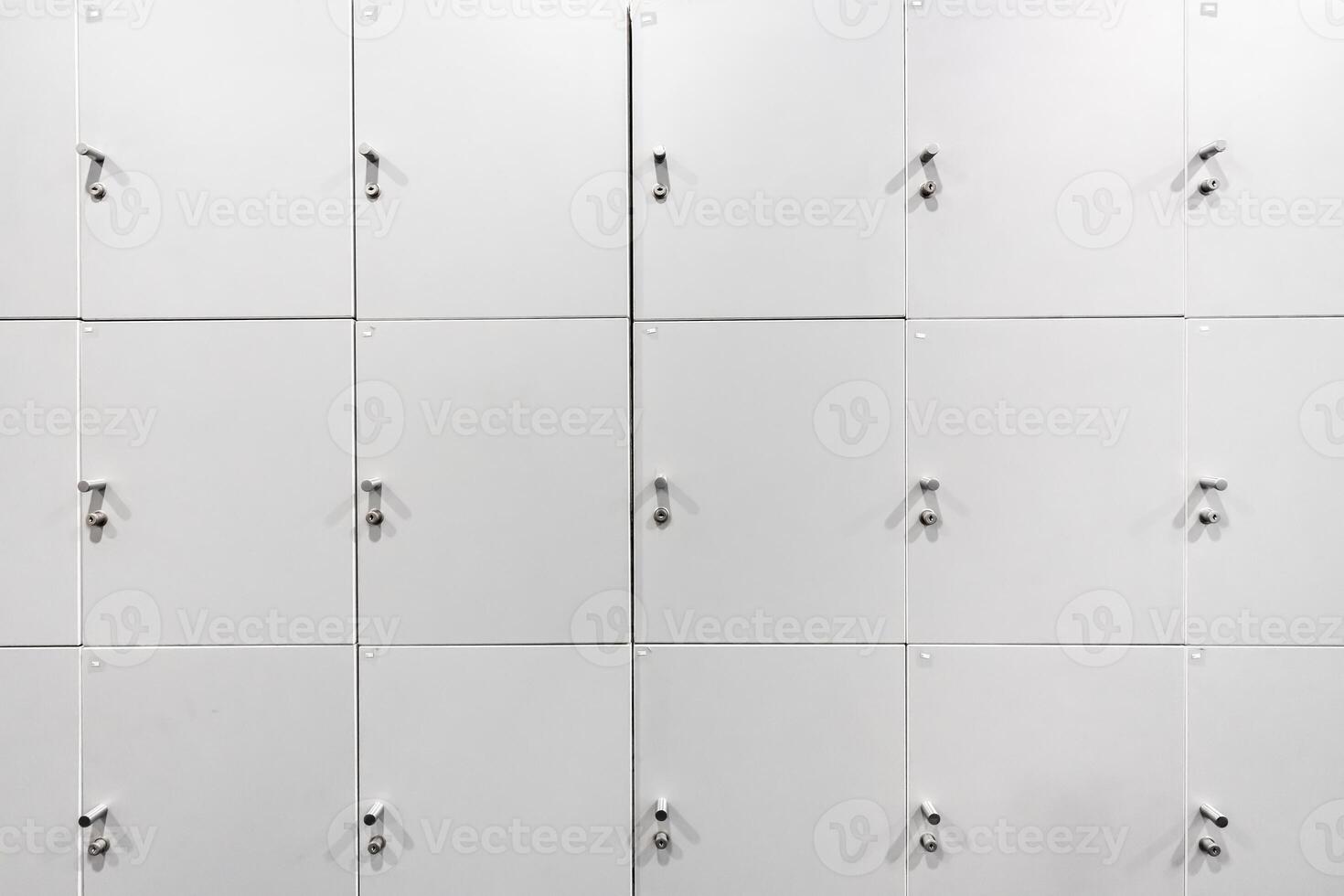 Large gray locker with each locker closed located beside corridors inside building are dimly lit. photo