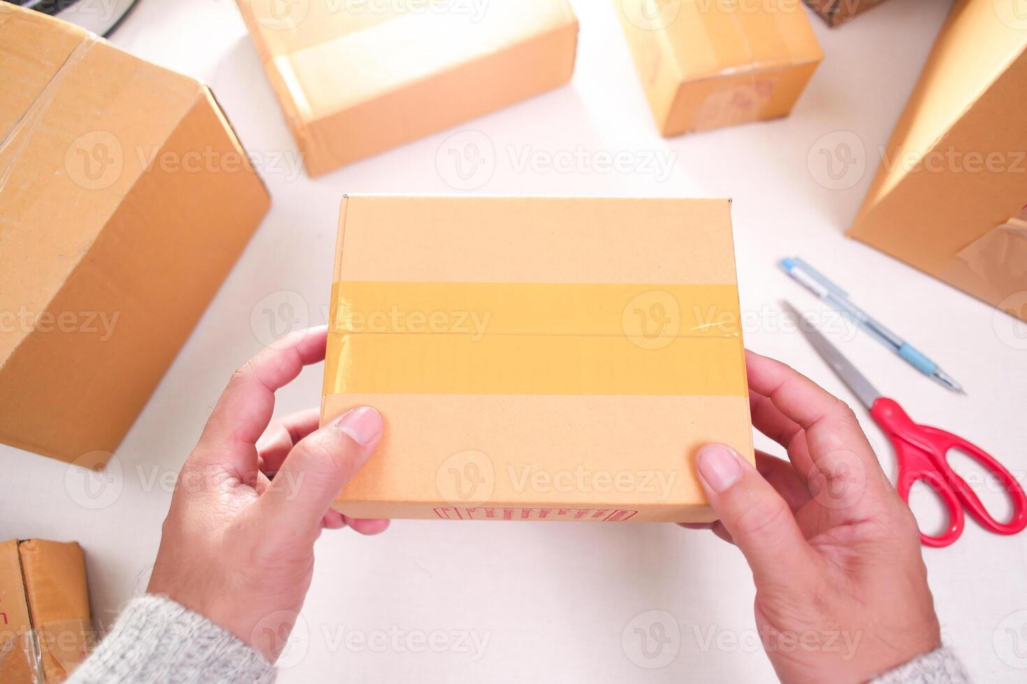 Goods delivery concept , human hand carrying a goods box and cardboard boxes placed on desk for product packing photo