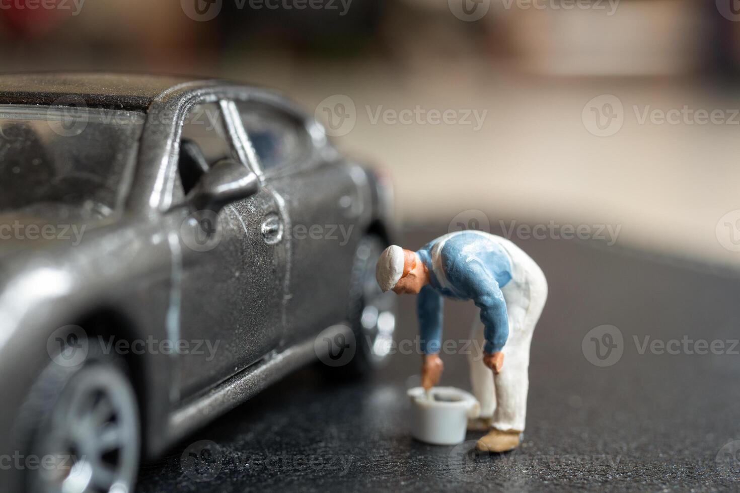 Miniature people, A worker bends over as if inspecting or repairing something on a sleek metallic gray car model photo