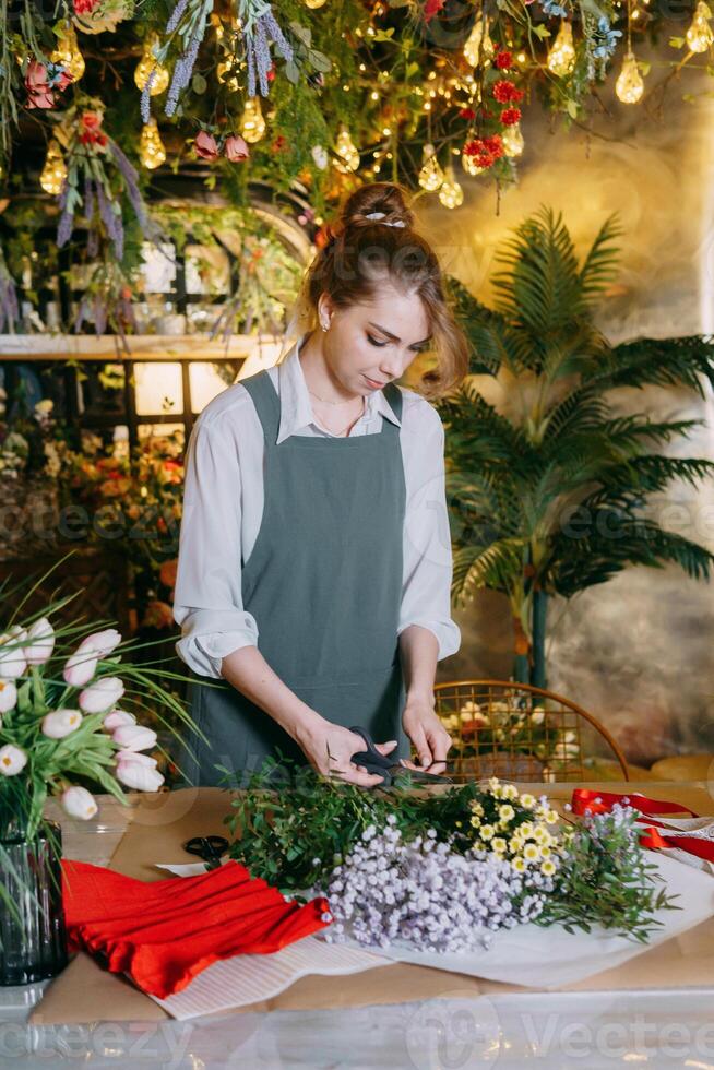 A woman in her florist shop collects bouquets of flowers. The concept of a small business. Bouquets of tulips for the holiday on March 8. photo