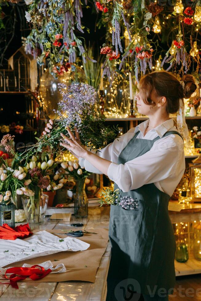 A woman in her florist shop collects bouquets of flowers. The concept of a small business. Bouquets of tulips for the holiday on March 8. photo