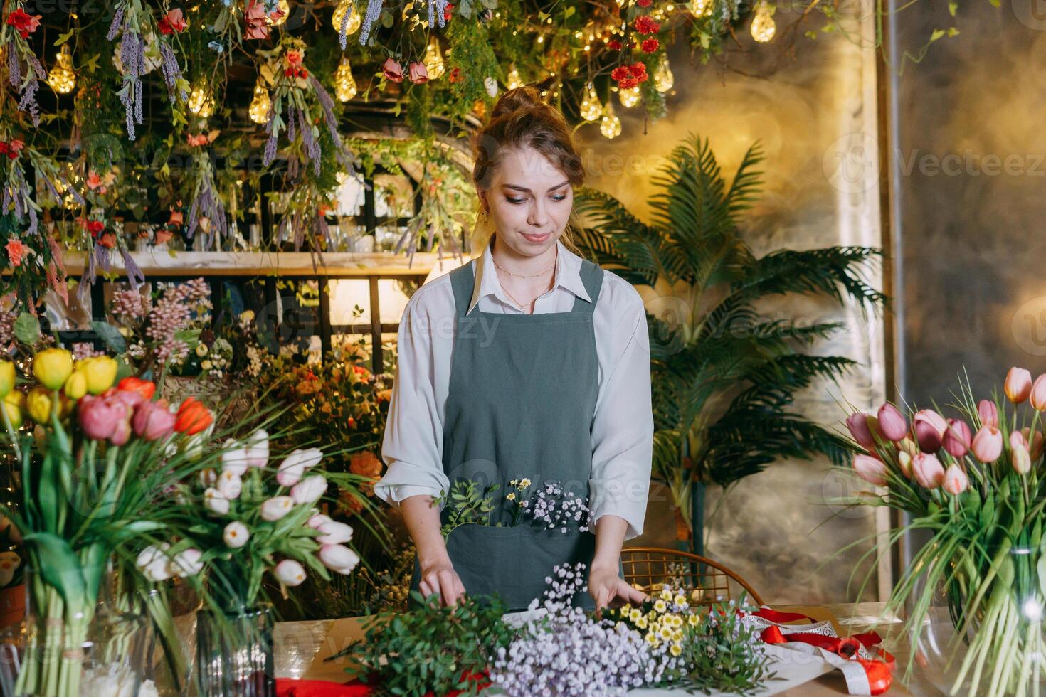 A woman in her florist shop collects bouquets of flowers. The concept of a small business. Bouquets of tulips for the holiday on March 8. photo