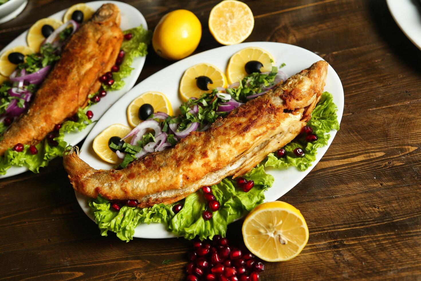 Fried Fish With Lemon and Pomegranate on Wooden Table photo