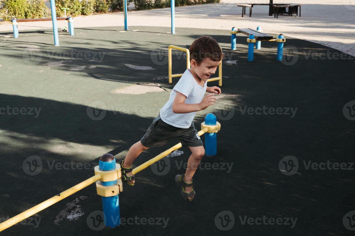 preschool child boy plays on horizontal bars on playground in park in summer photo