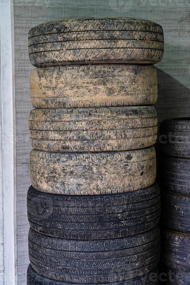 Stacked Used Tires Against Wall photo