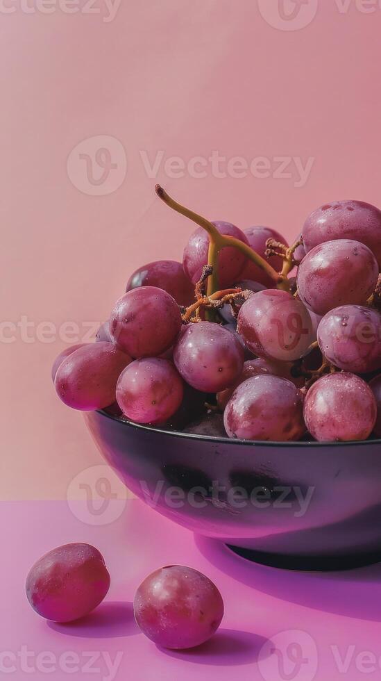 A bowl of red grapes on a pink background photo