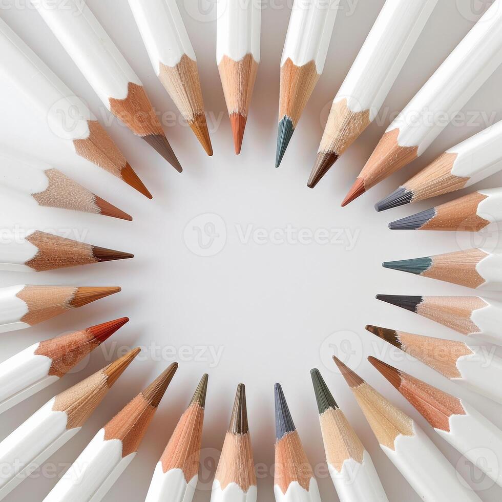 White pencils arranged in a circle on a light surface, showcasing a rainbow of colors photo