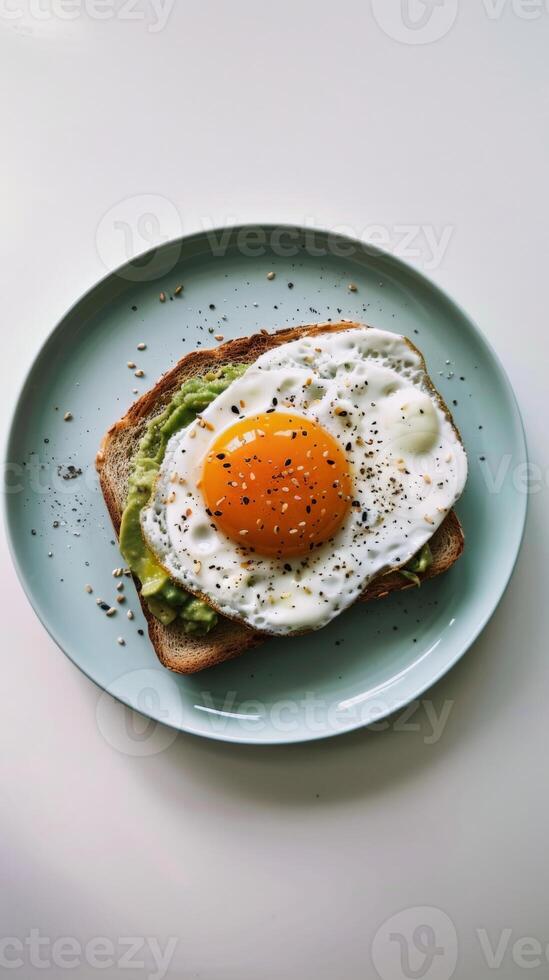 A single slice of avocado toast topped with a perfectly fried egg photo