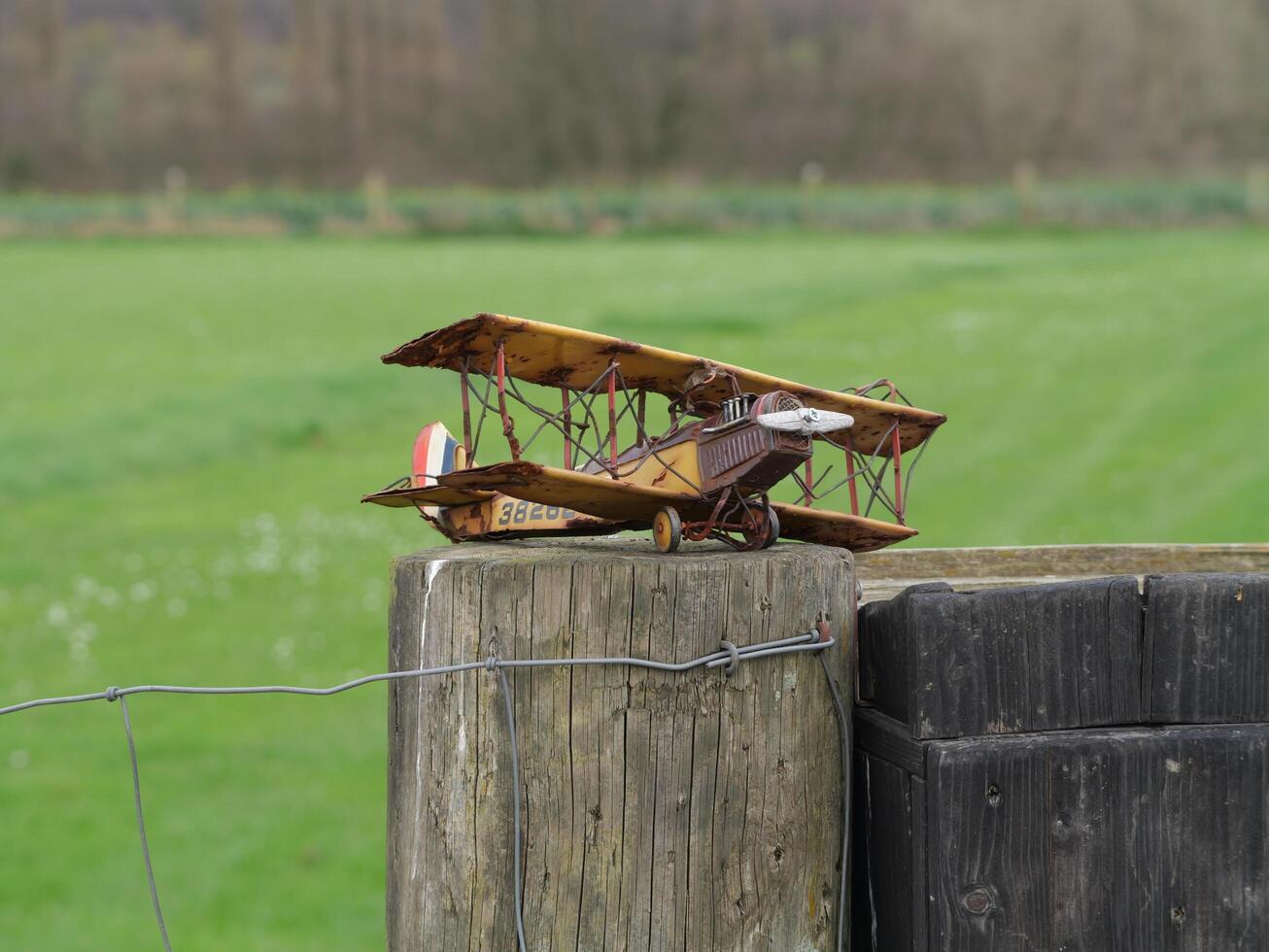 a small model airplane sitting on a fence post photo