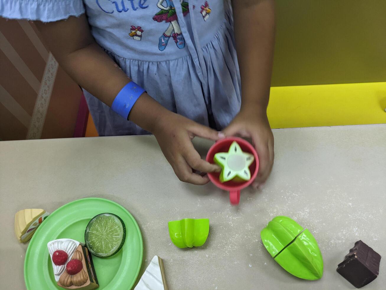 Child Playing with Play Food. A young child playing with plastic toy food, setting a table with cakes and fruit. photo