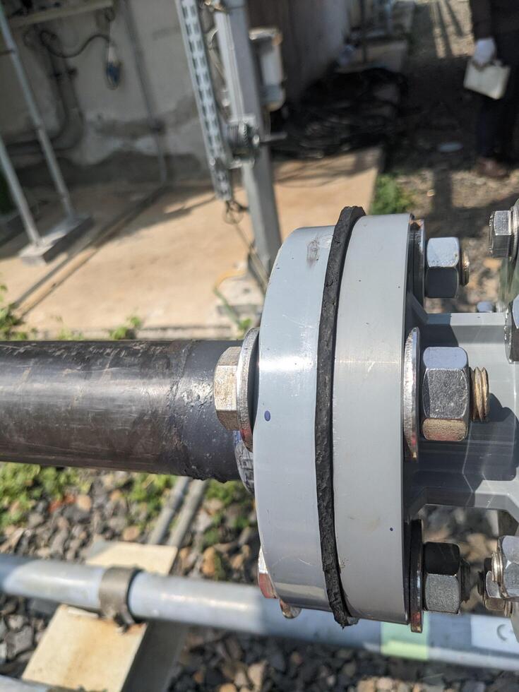 Close-up of Pipe Joint. A close up view of a pipe connection, showing the metal pipe, weld, and the nuts and bolts securing the joint. photo