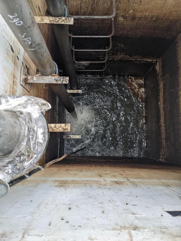 Looking Down into an Open Manhole Water Drainage System Power plant. A close-up view looking down into an open manhole revealing the dark depths below. photo
