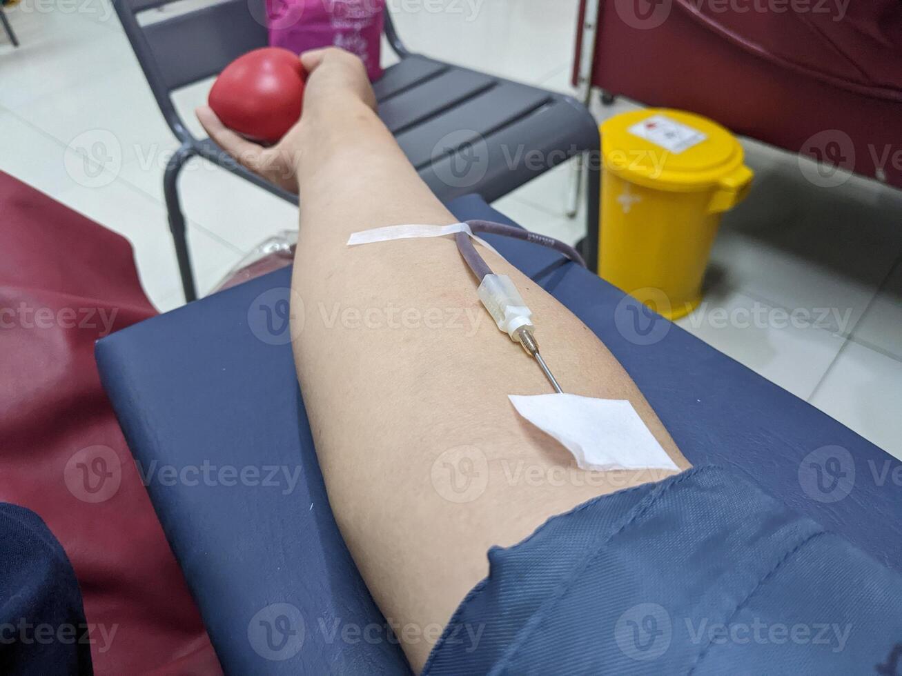 A person's arm with a needle inserted for blood donation. Photo is suitable to use for health poster and blood donation content media.