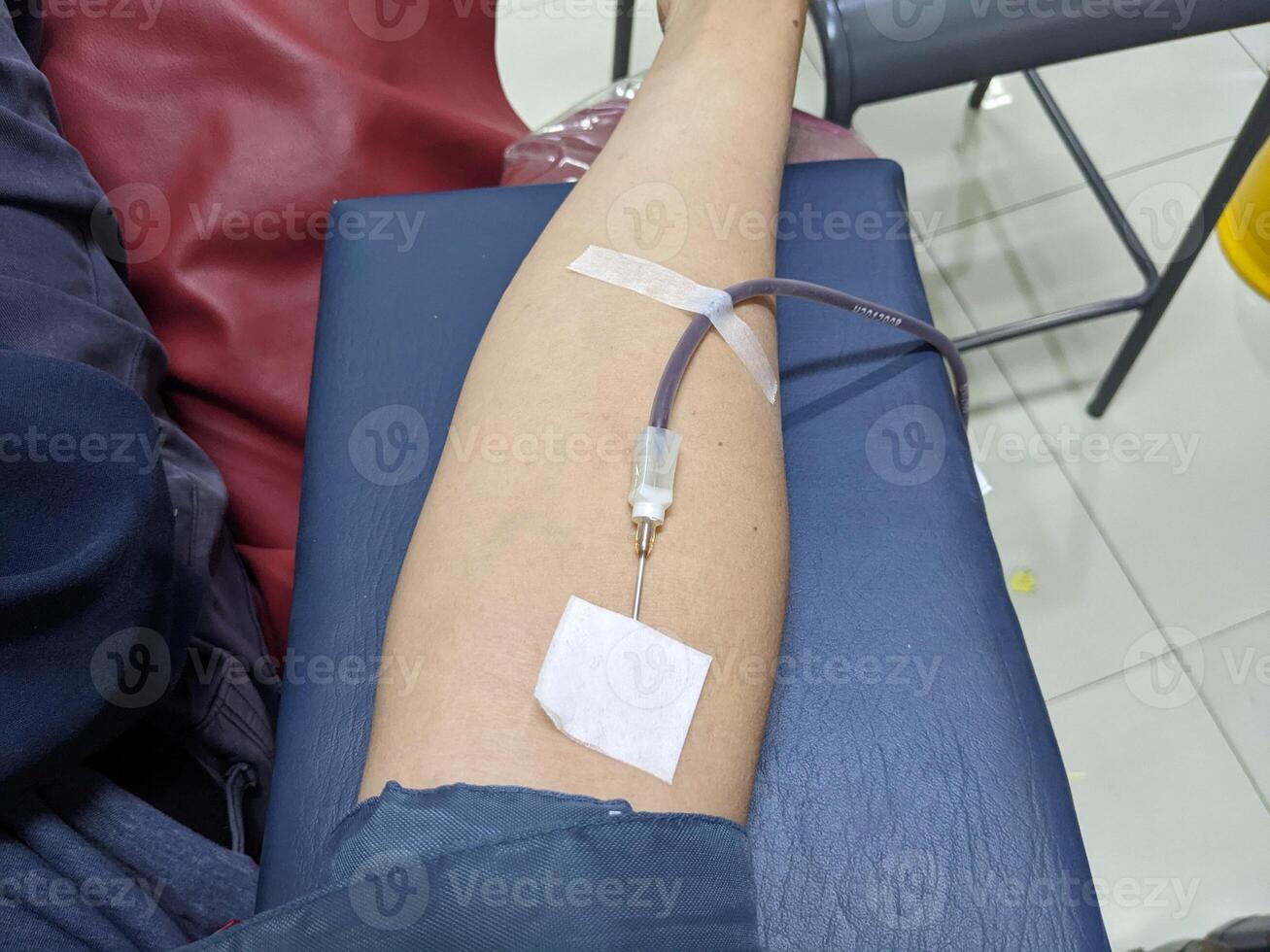 A person's arm with a needle inserted for blood donation. Photo is suitable to use for health poster and blood donation content media.
