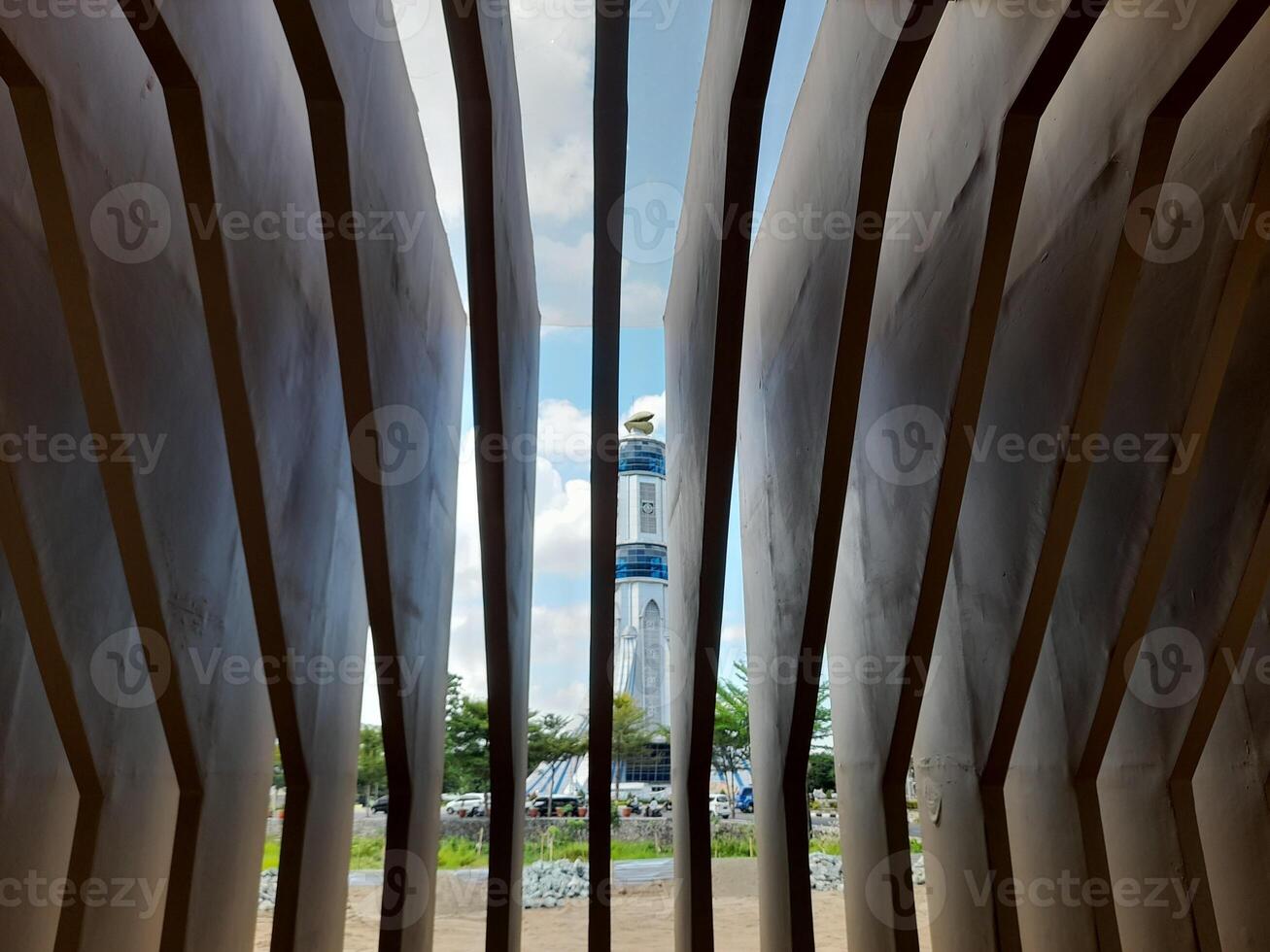 A monument seen through the gap in the building's exterior signage. photo