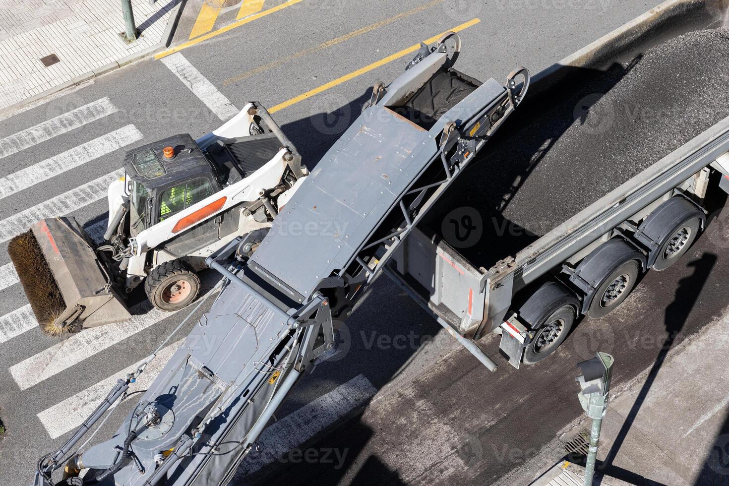 Road maintenance with a Milling machine working and removing asphalt from the city road and pouring it into a truck photo