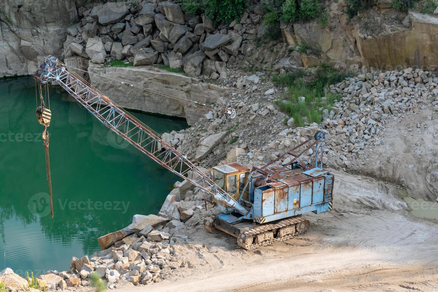 Mining in the granite quarry. Working mining machine - old crane. Mining industry. photo