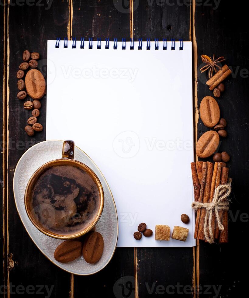Coffee, sugar, cinnamon, cookies and open notebook photo