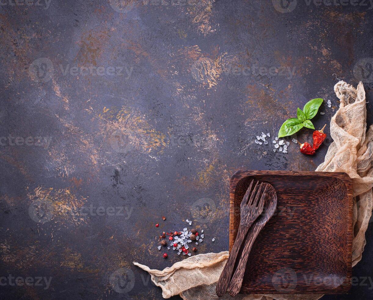 Empty wooden plate, cutlery, salt, pepper and basil photo