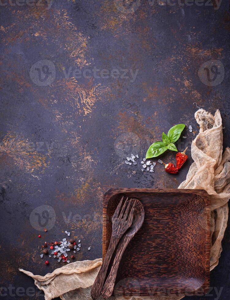 Empty wooden plate, cutlery, salt, pepper and basil photo
