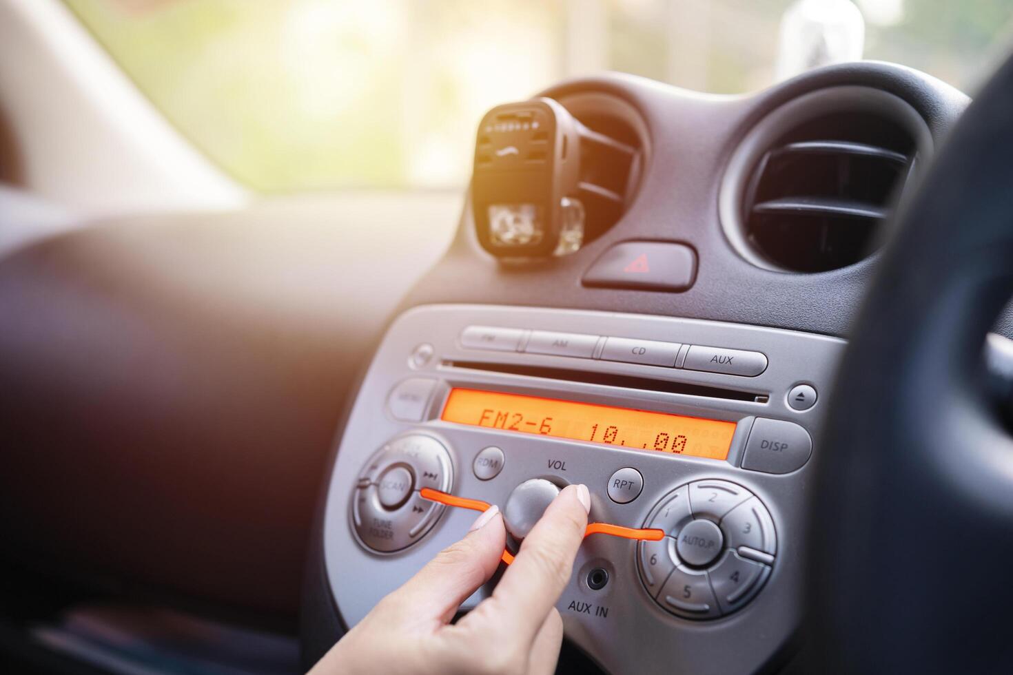 Women turning button on car radio for listening to music photo