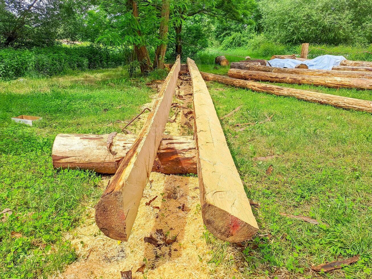 Planks and logs lie on the grass by the river, seasoning for building a raft. photo