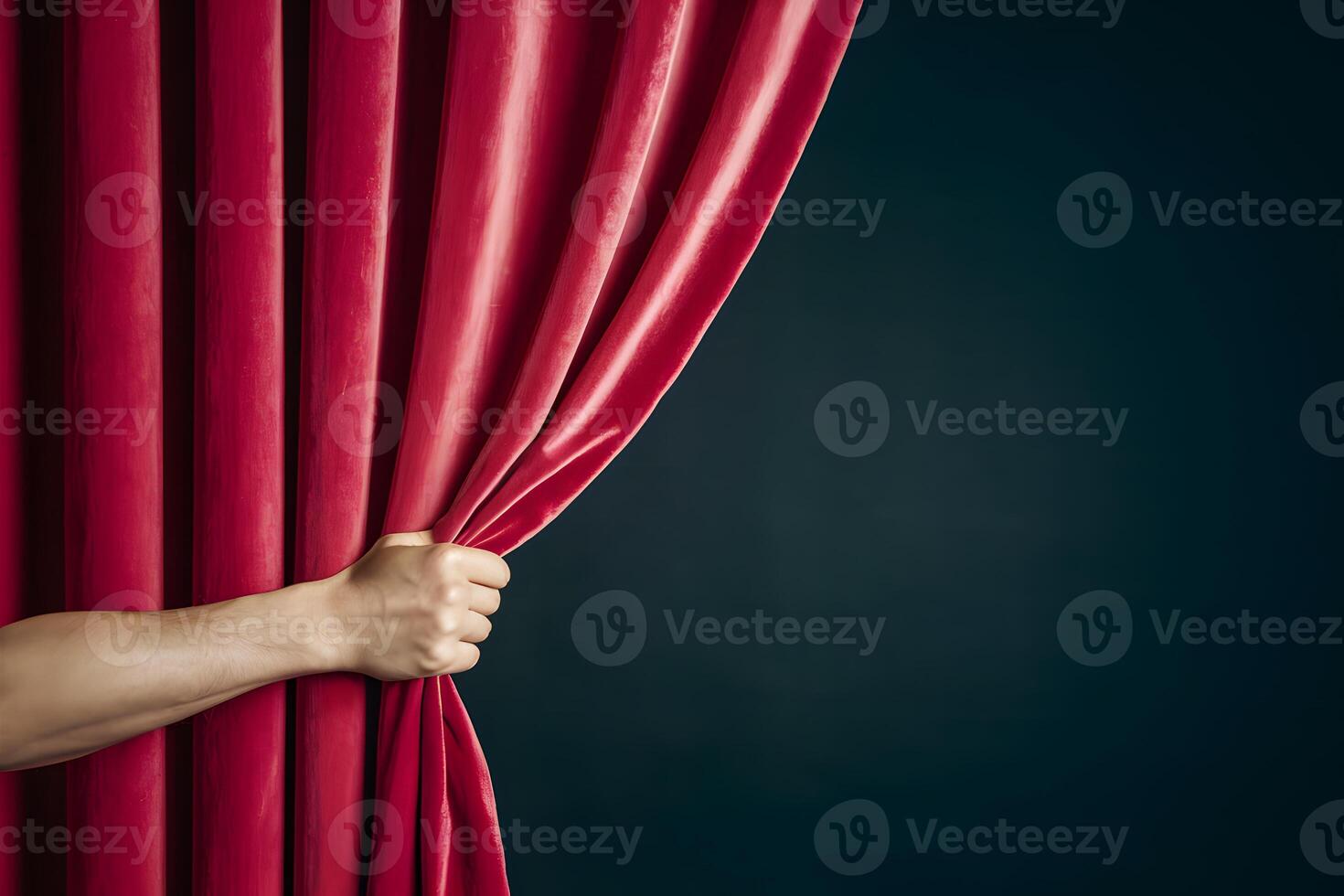 Hand pulls open vibrant red curtain against dark background, stage setting photo
