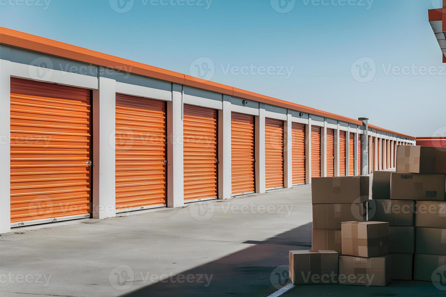 Row of self storage units with bright orange doors, stacked cardboard boxes photo