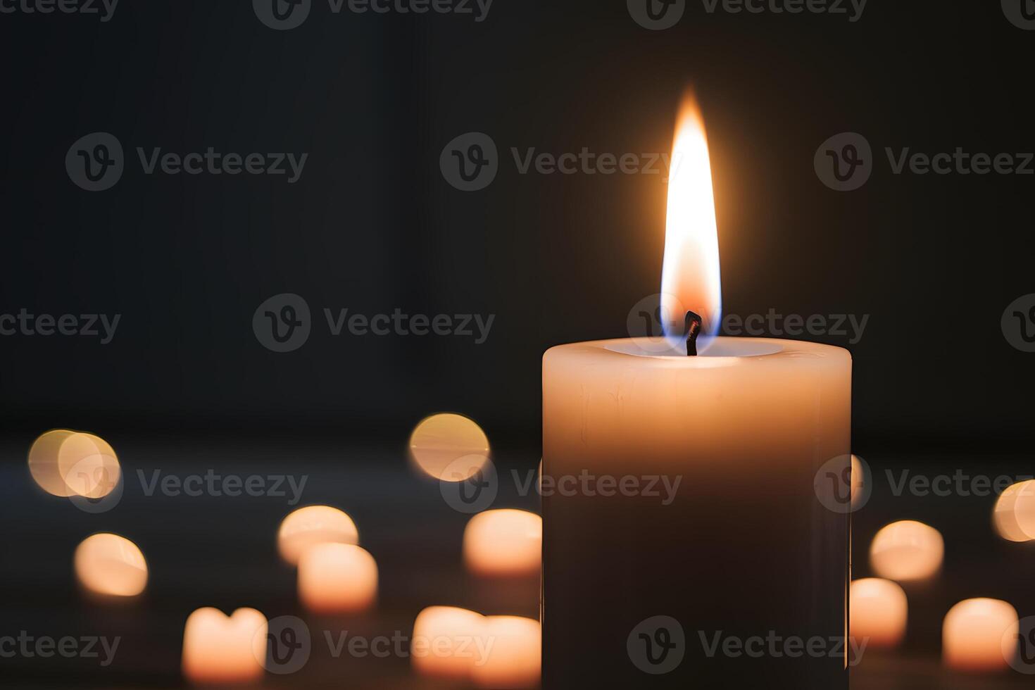 Tall candle with steady flame against dark background photo