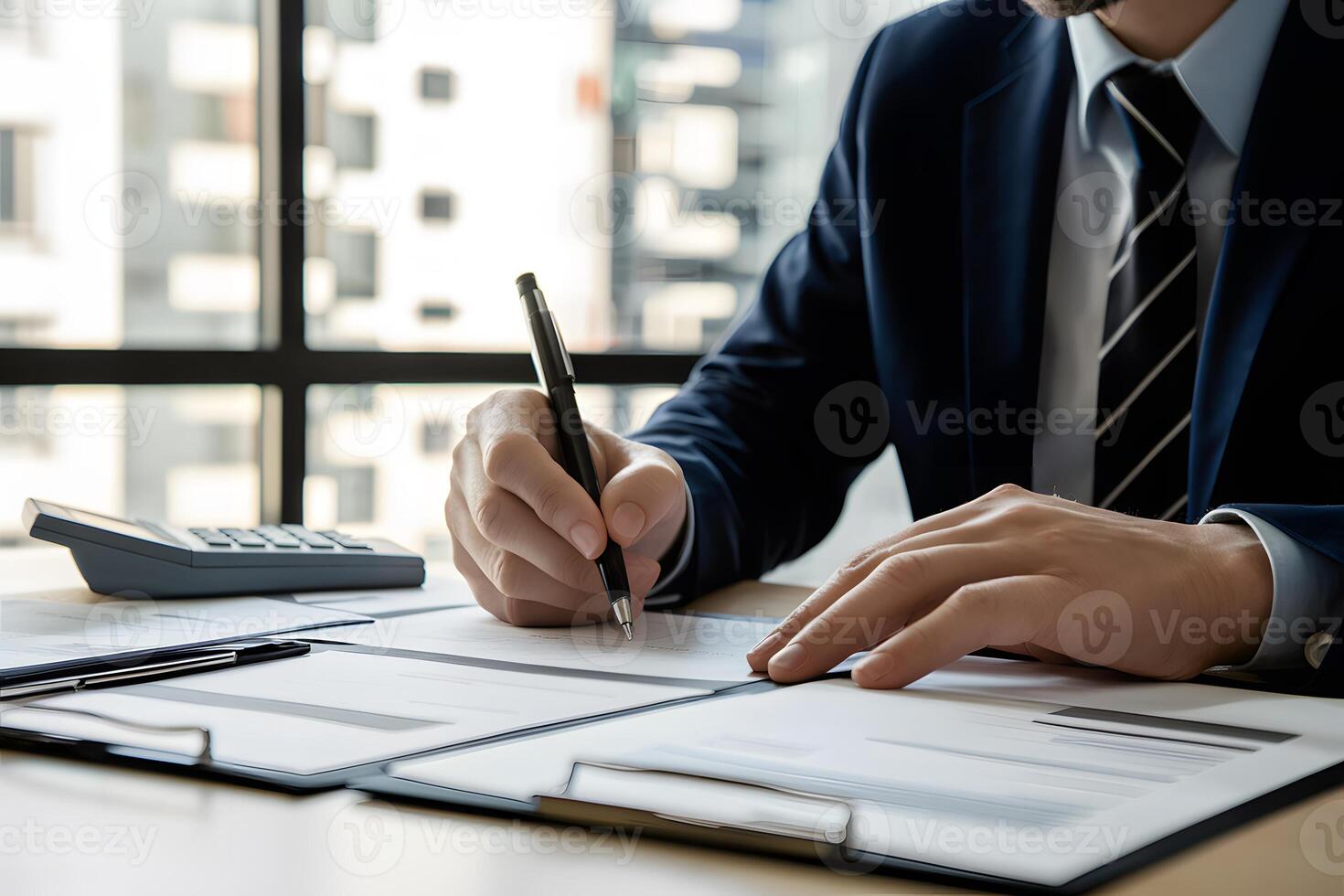 Man in suit writing at desk with window, documents and calculator photo