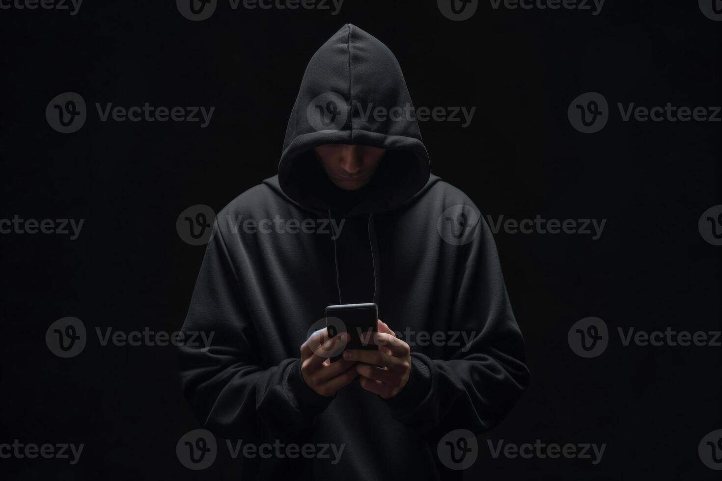 Hacker in black hoodie using smartphone in in the dark, cybercrime concept photo