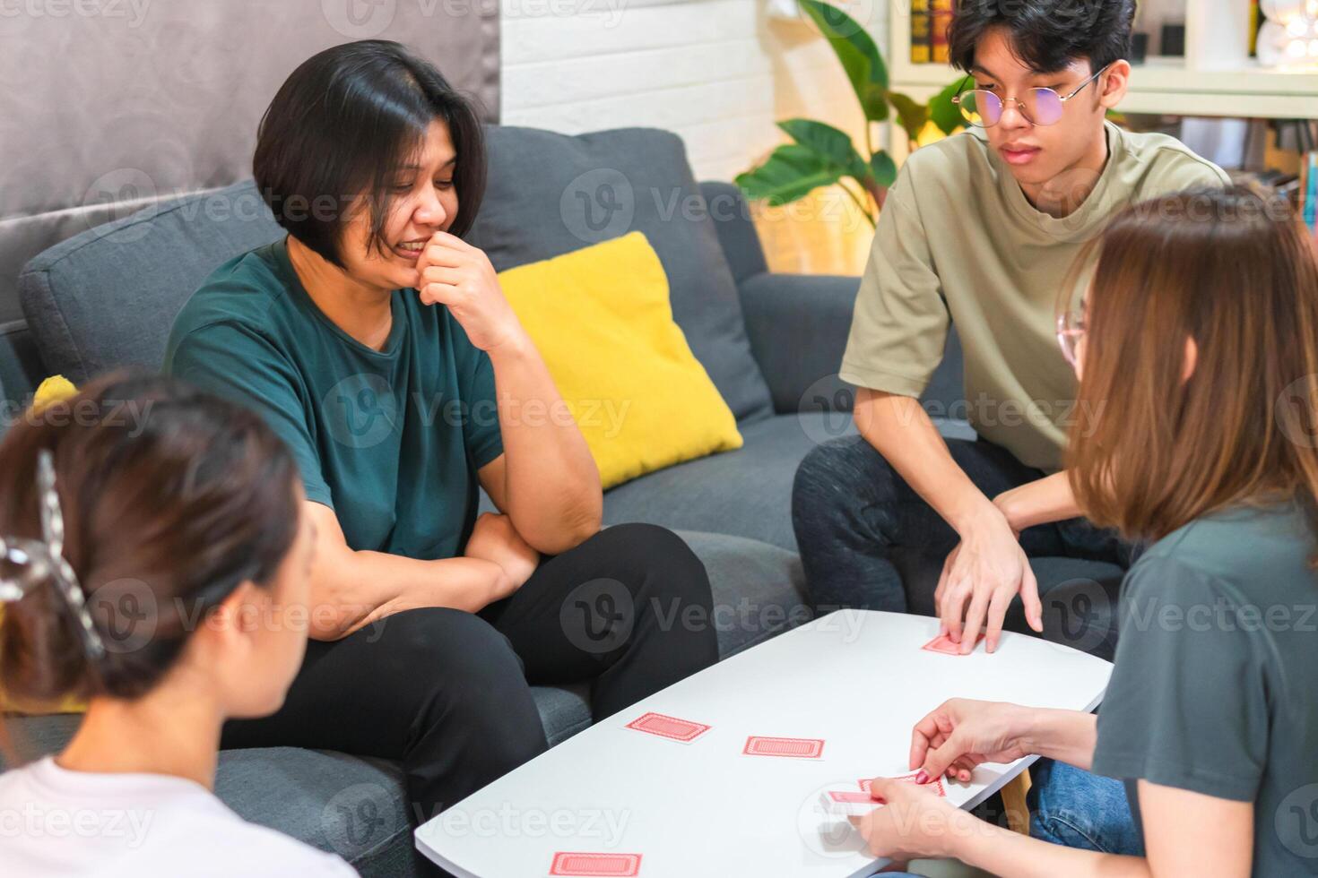 Asian family playing games together, Diverse people playing a card game in the living room photo