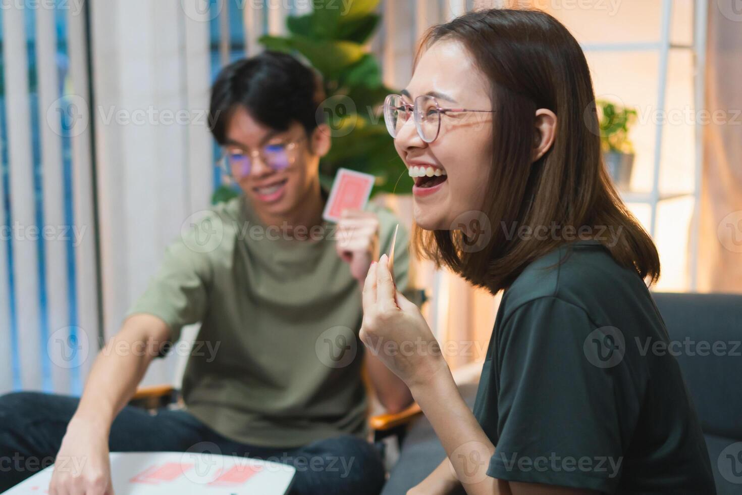 Asian family playing games together, Diverse people playing a card game in the living room photo