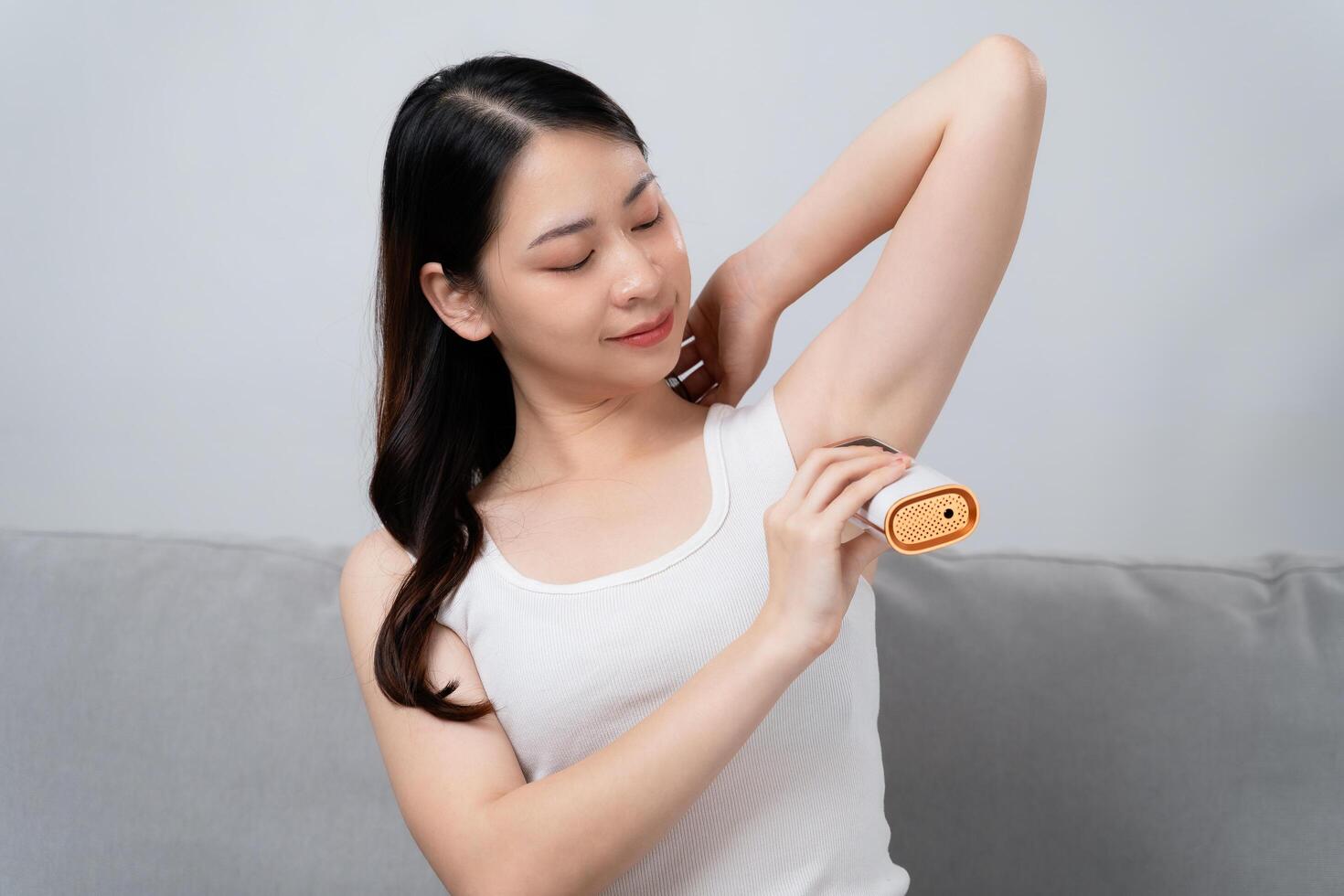 A beautiful woman is epilating her armpits using an IPL laser hair removal photo