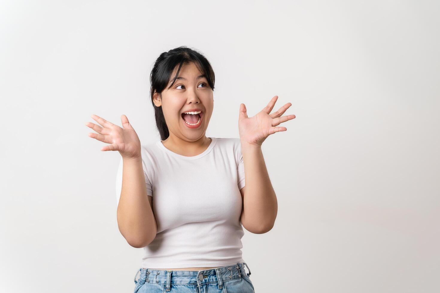 A woman with a big smile on her face is wearing a white shirt and blue jeans photo