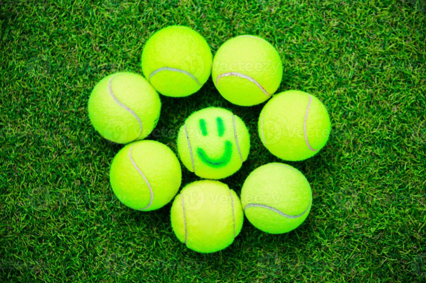 Tennis Balls Arranged in a Circle on Grass with a Smile photo