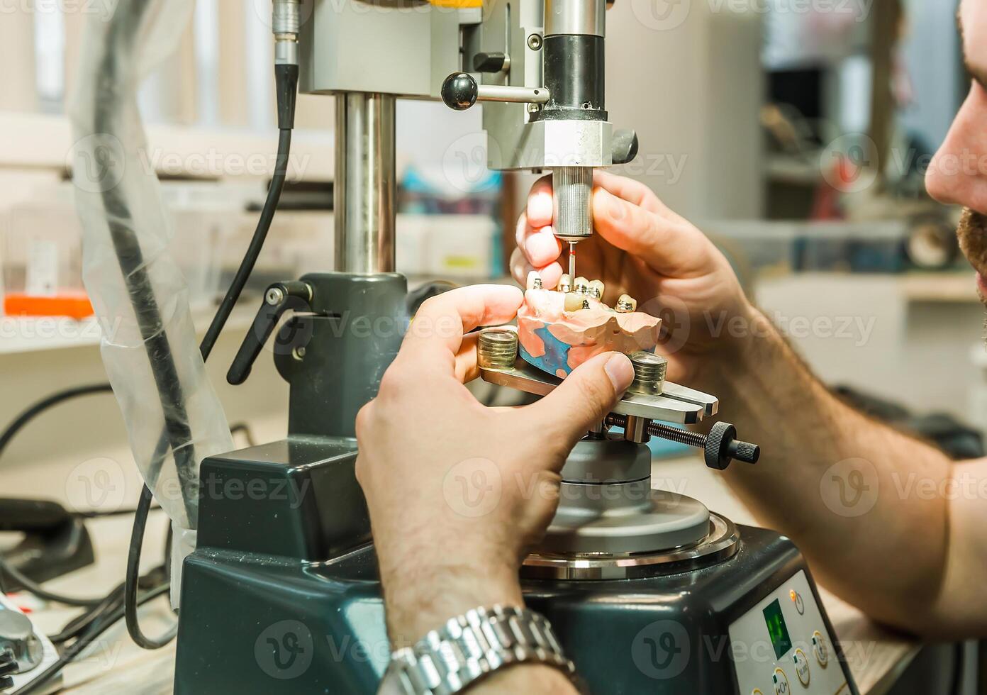 Technician using dental drill on a dental mold photo