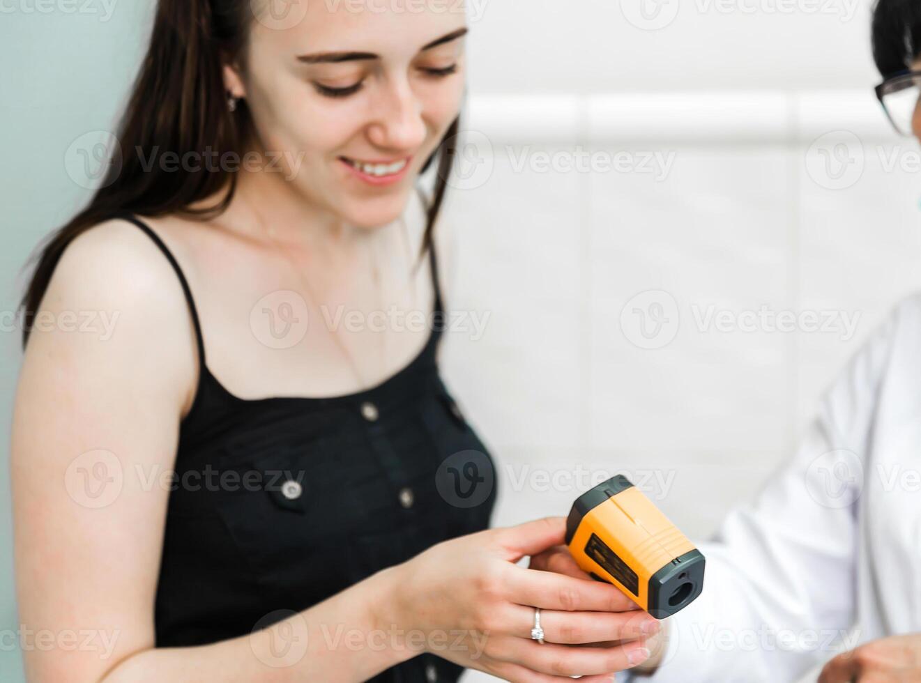 Woman Holding Infrared Thermometer During Temperature Check photo