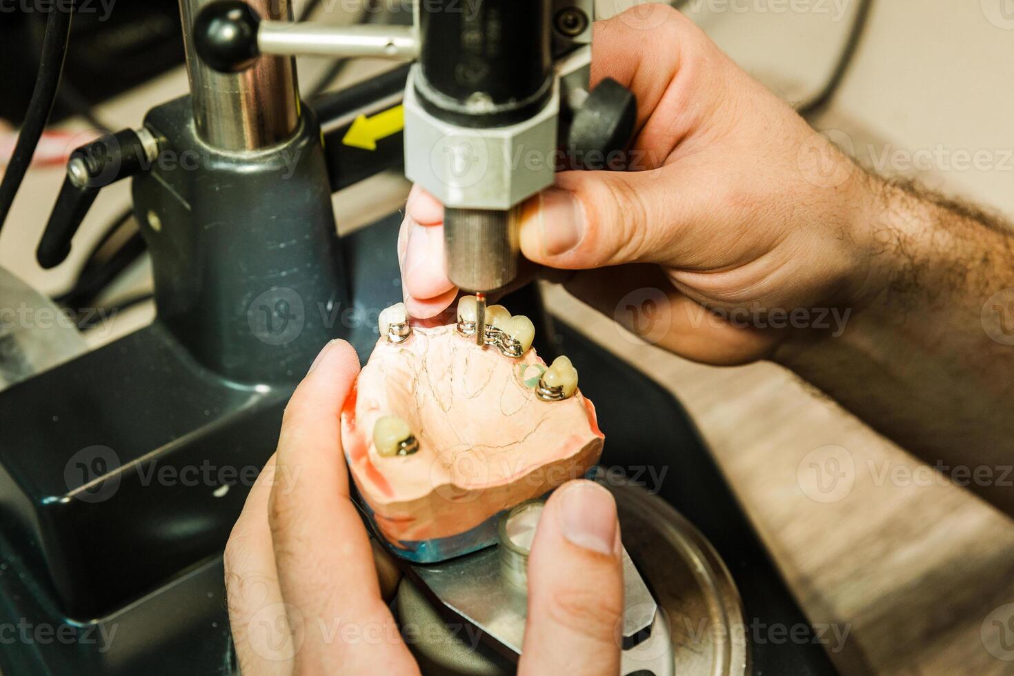 Technician operating dental drill on dental mold in lab photo