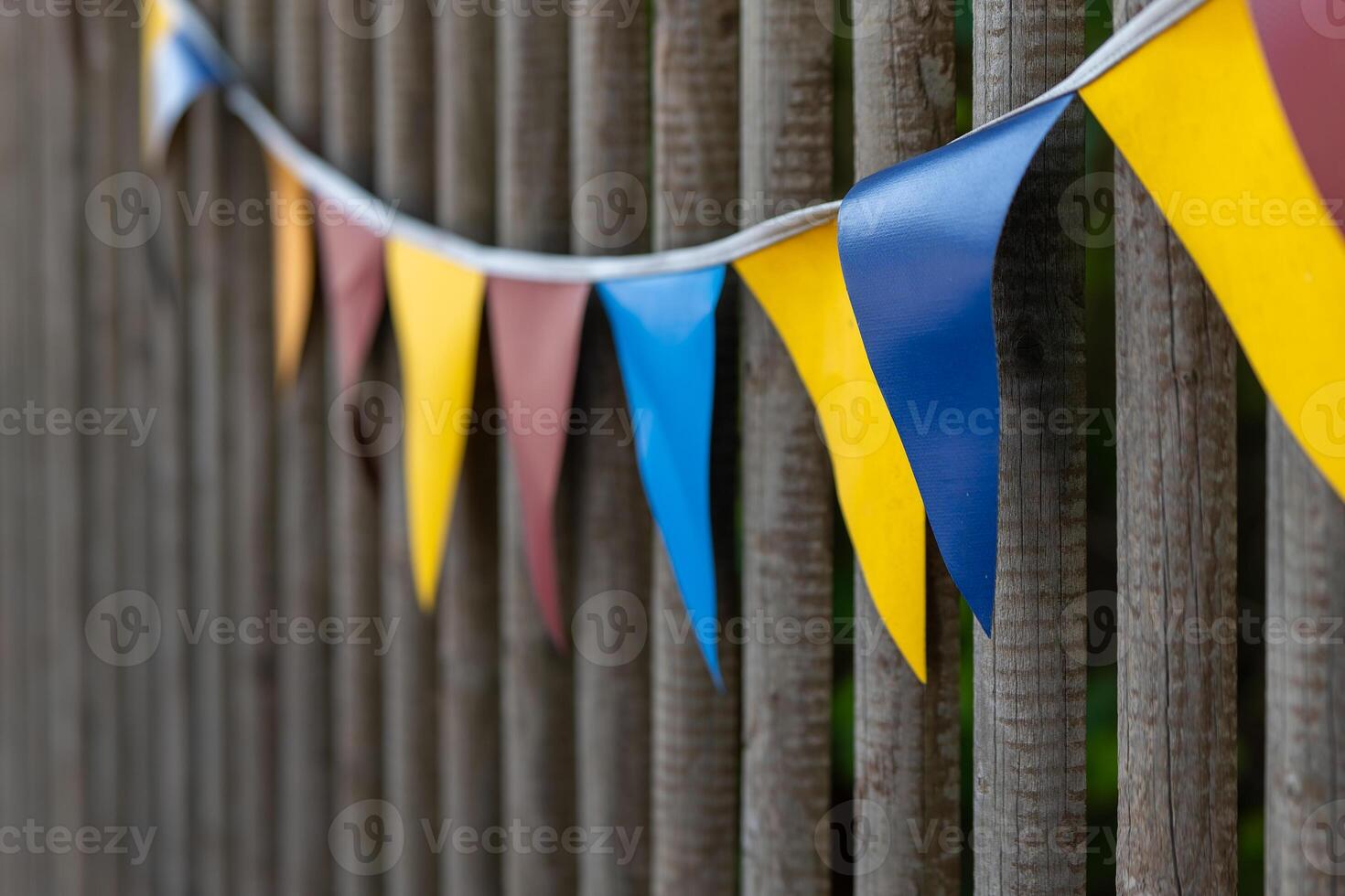 row of flags hanging from a wooden fence photo