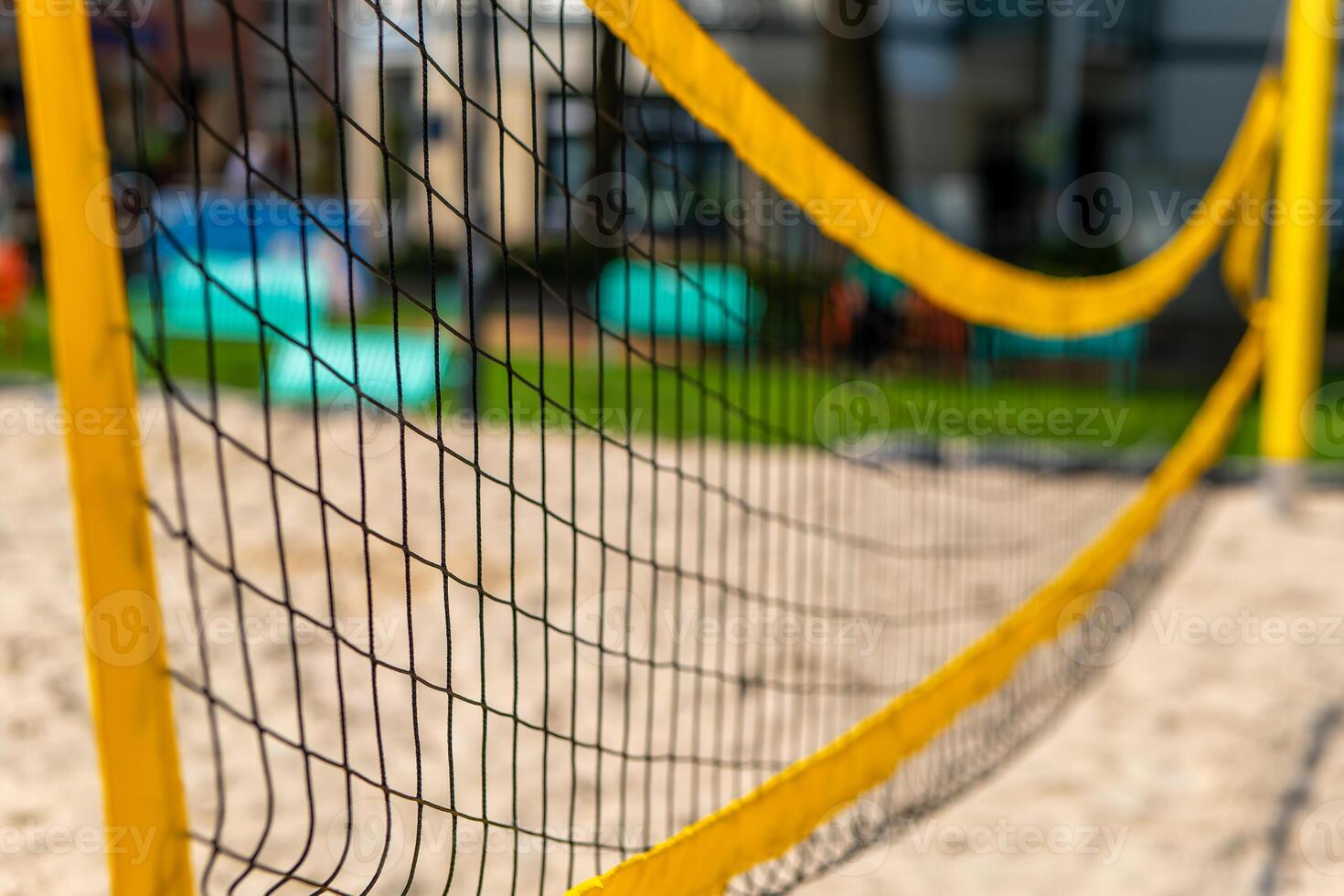 yellow volleyball net is stretched across a sandy beach photo