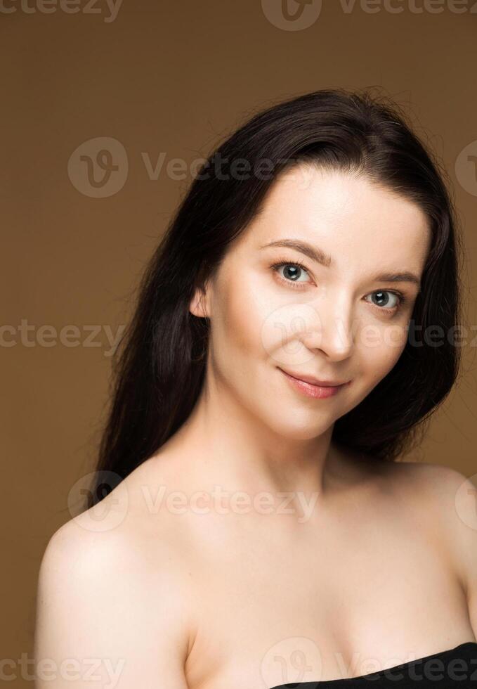 Young woman with dark hair on beige background photo