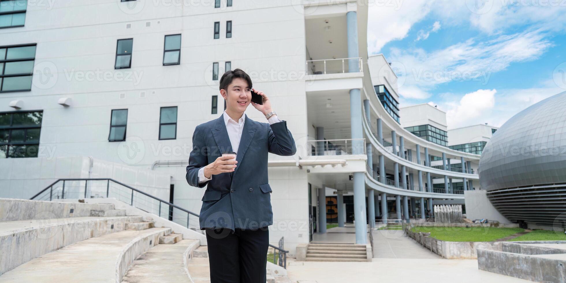 Businessman Talking on Phone Outside Modern Office Building with Coffee in Hand on a Sunny Day photo