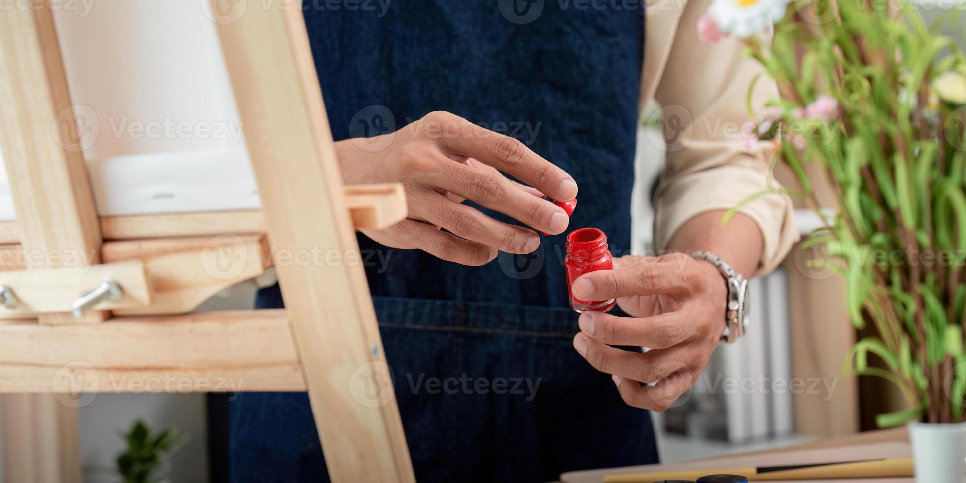 Artist Preparing Red Paint for Canvas Painting in a Bright Studio with Flowers in the Background photo