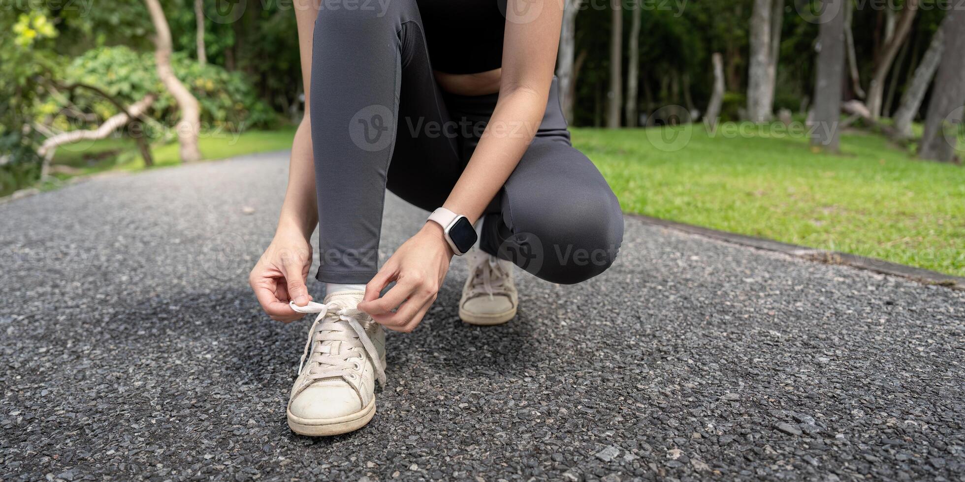 Woman Tying Shoelaces on Running Shoes in Park, Preparing for Outdoor Exercise in Nature photo