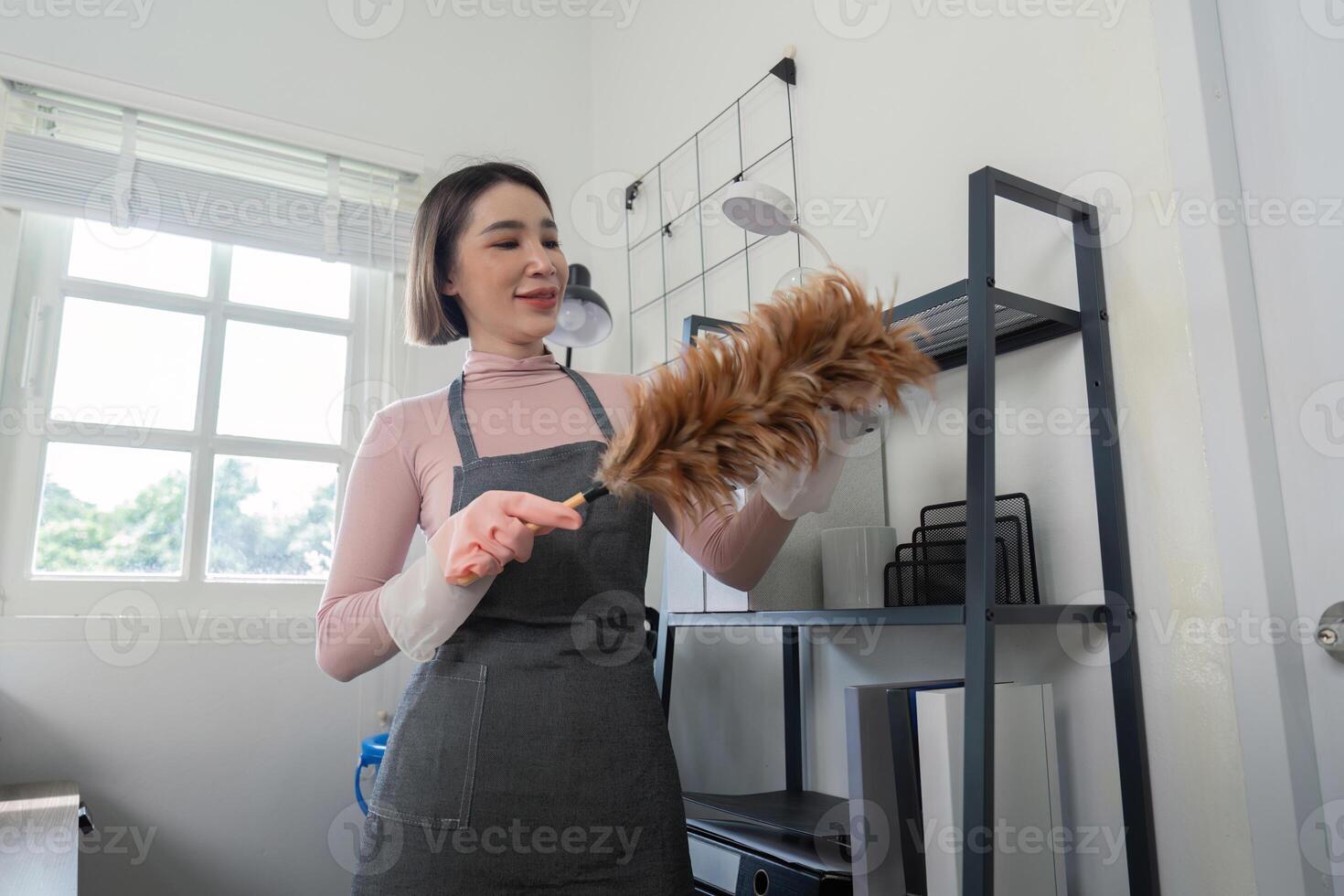 Professional Housekeeper Dusting Shelves in Modern Home Interior with Feather Duster photo