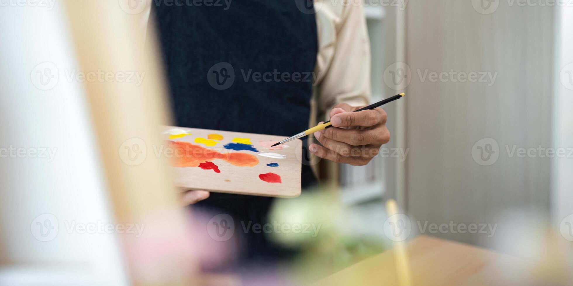 Artist Holding Paintbrush and Palette with Colorful Paints in Studio Setting, Creative Art Concept photo