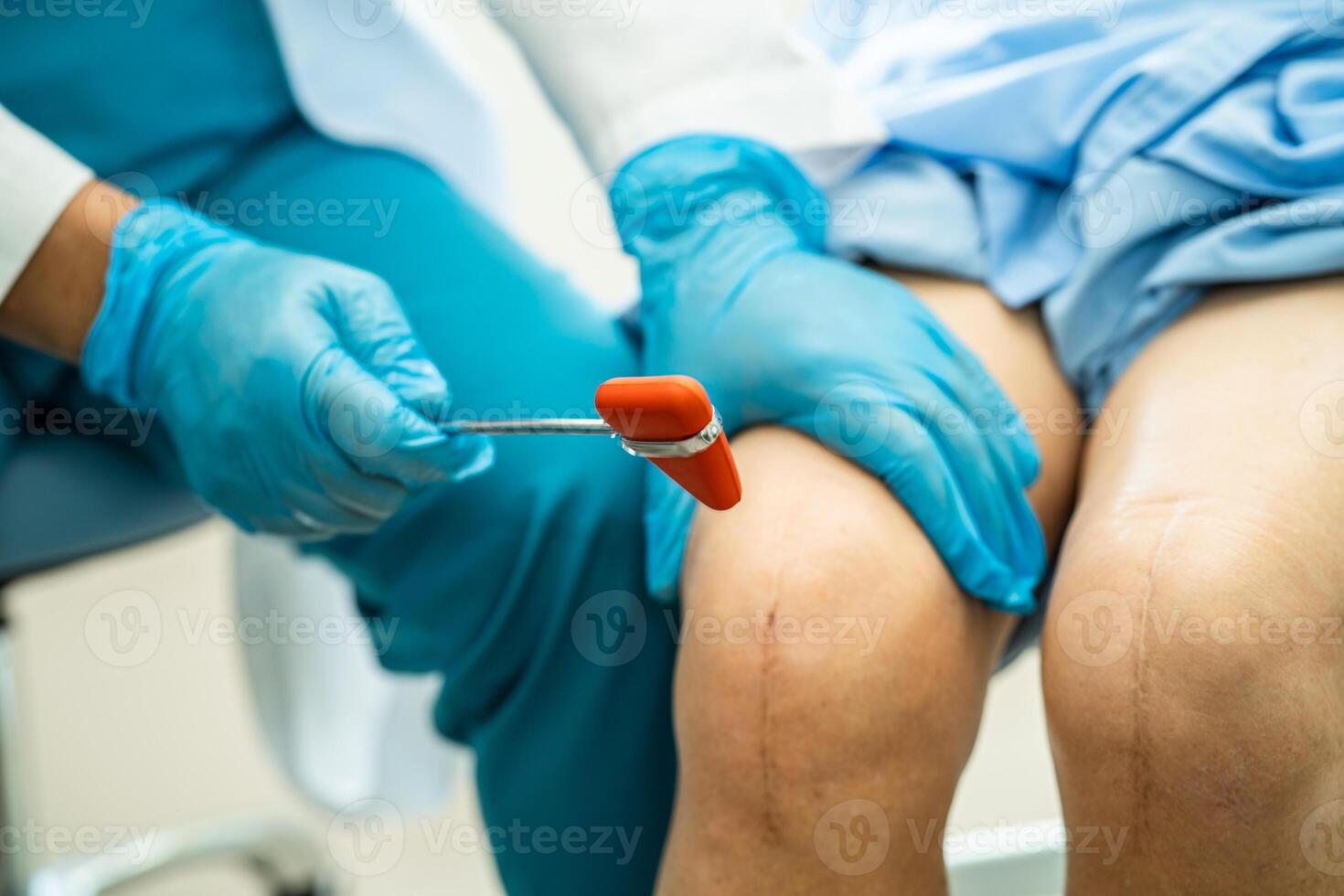 Asian doctor use hammer knock senior woman patient to check knee reflex, nerve and muscle in hospital. photo